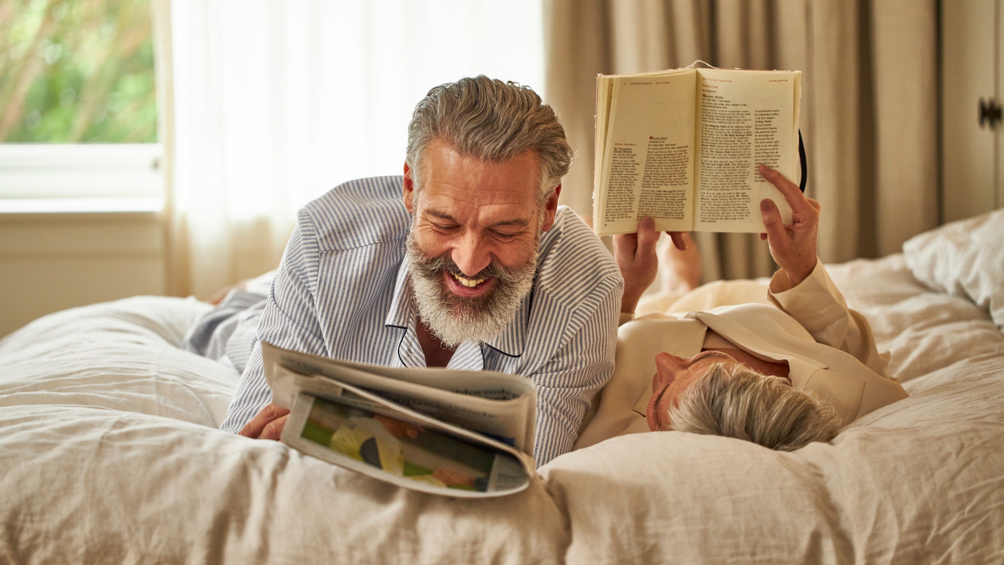 Un couple d'âge moyen se détend joyeusement sur son lit et profite de la température parfaite.