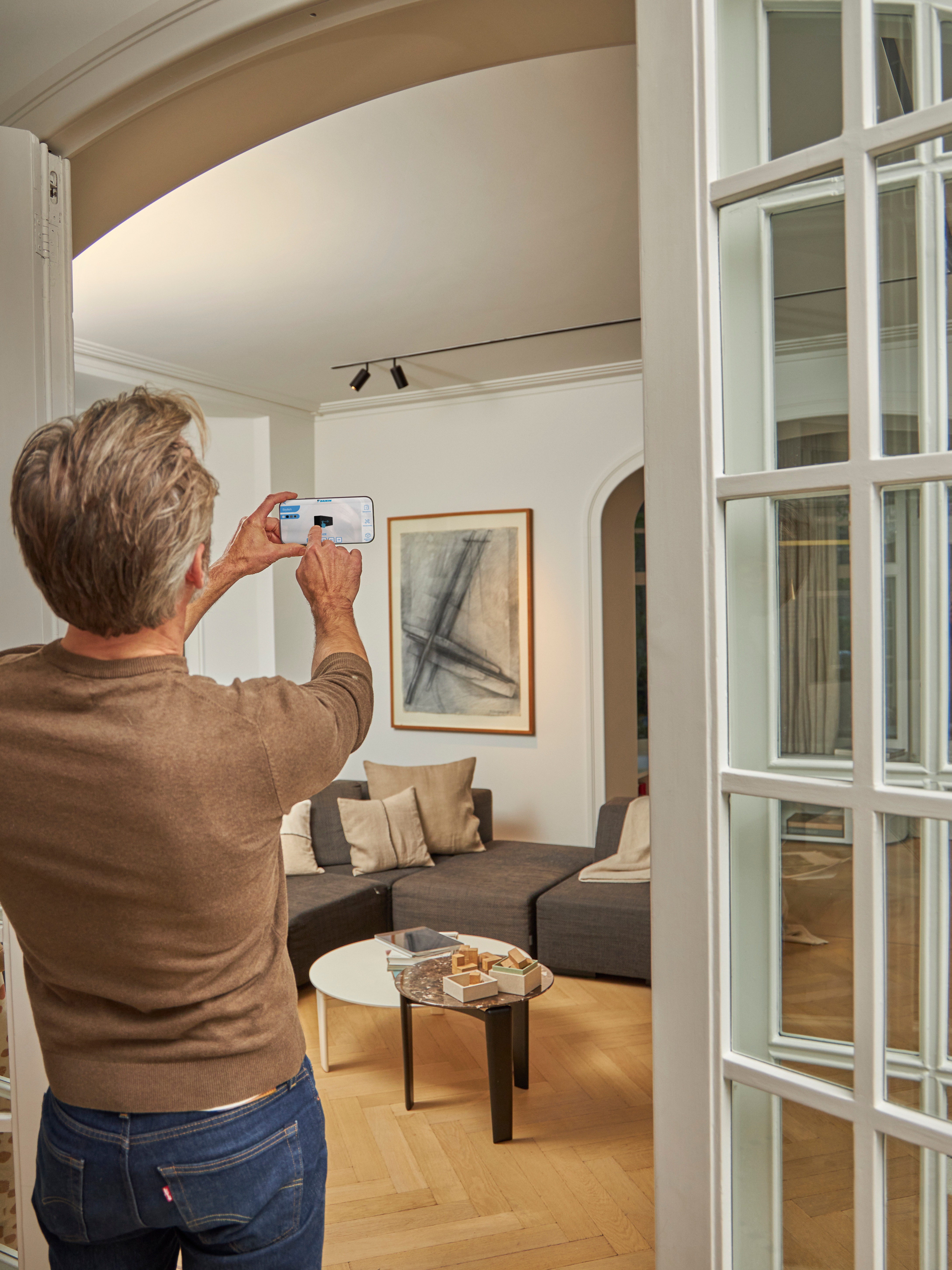 Homme utilisant l'application 3D pour visualiser une unité intérieure dans son salon.