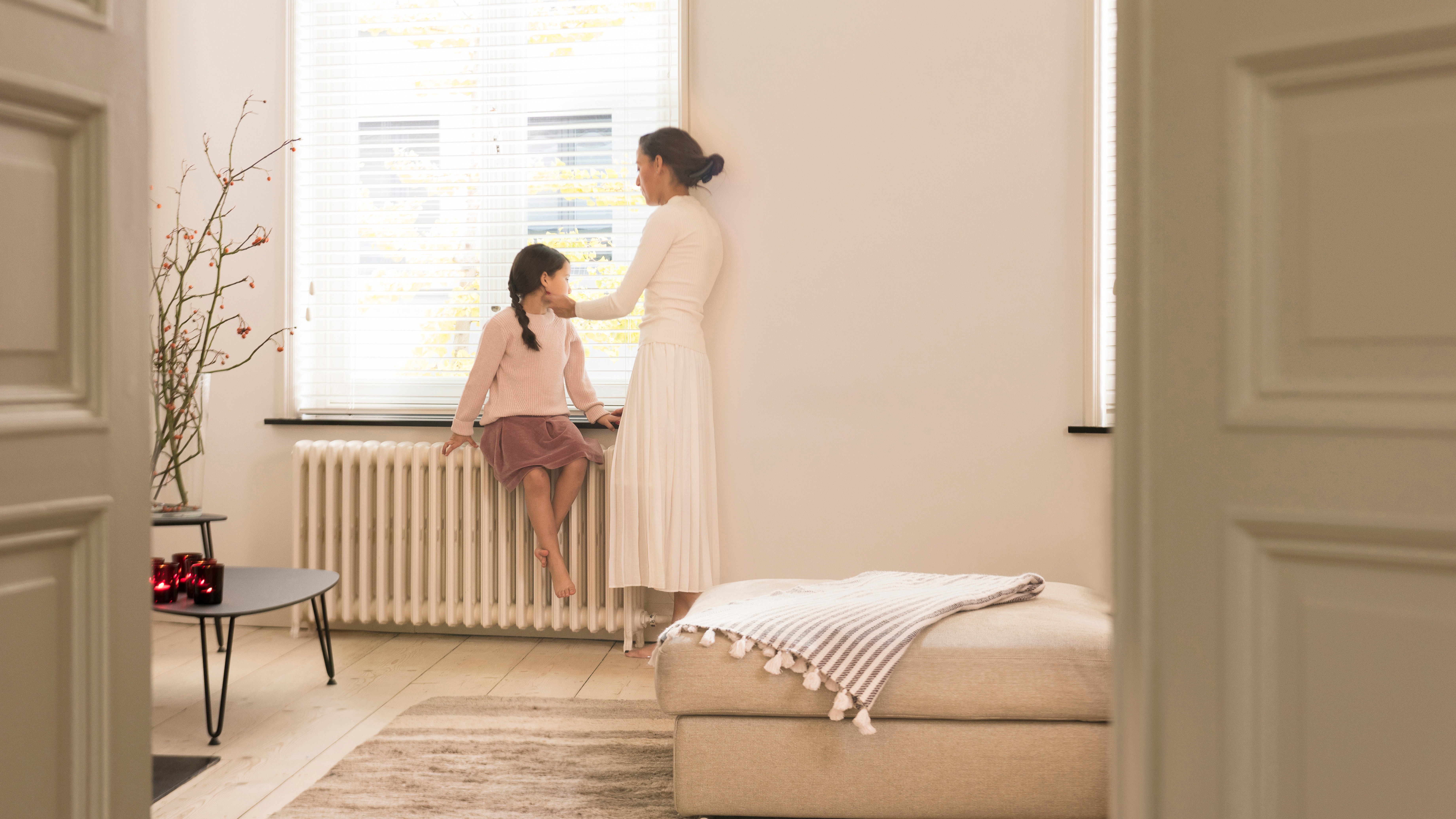 Maman et sa fille discutant et se réchauffant contre le radiateur