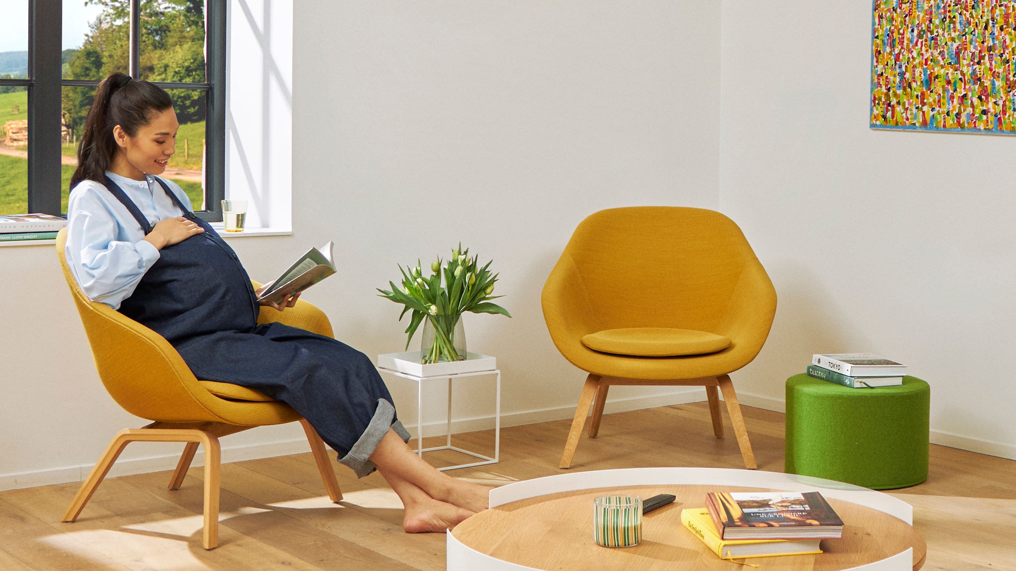 Femme enceinte lis un livre dans son fauteuil et profite de l'air sain dans son salon.