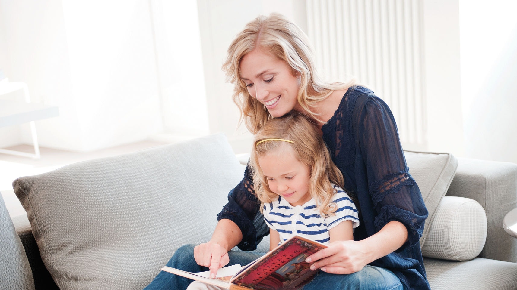 Mère et fille lisant un livre sur le canapé, profitant d'un climat intérieur parfait