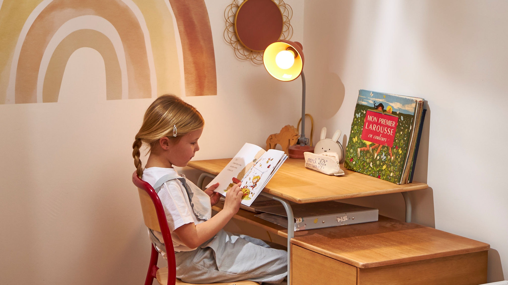 Petite fille lisant un livre pour enfants à son petit bureau
