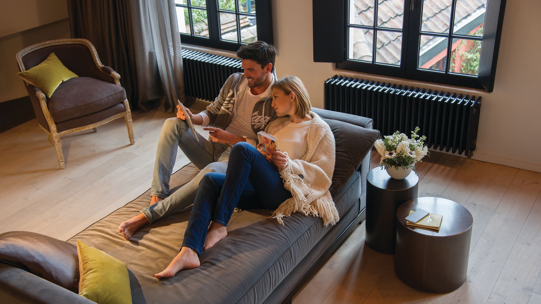 Couple se relaxant sur un canapé et regardant quelque chose sur leur tablette