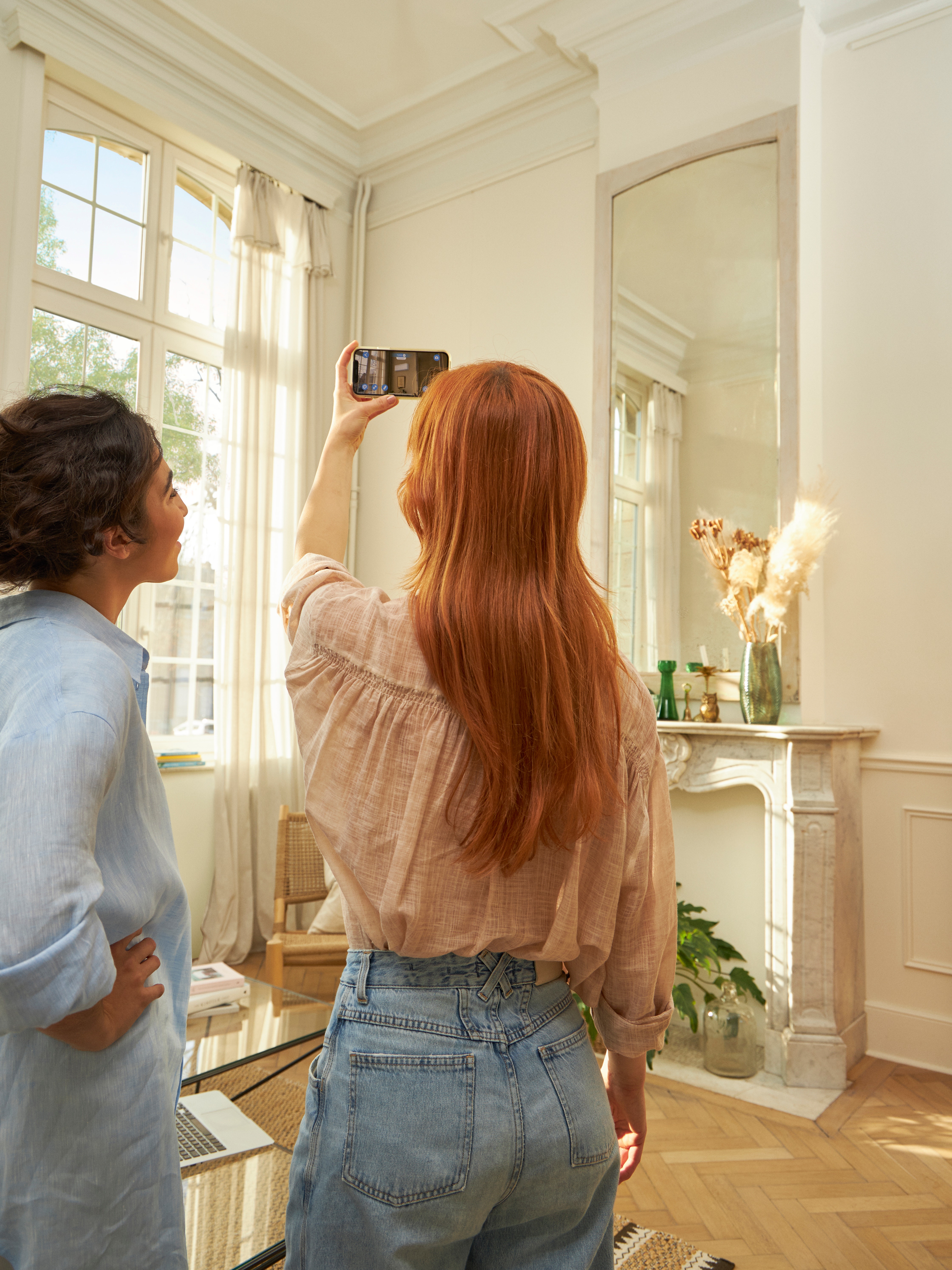 Femme visualisant sur son application 3D une pompe à chaleur air/air dans l'intérieur de son salon.