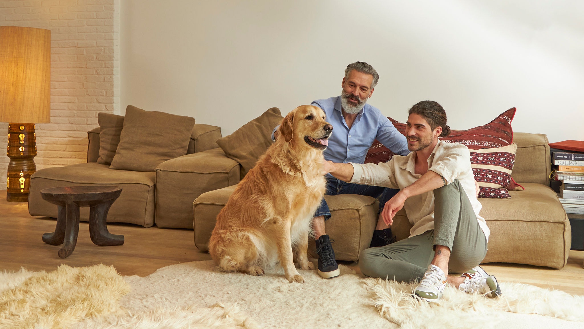 Deux hommes caressent un chien dans leur salon confortable et climatisé